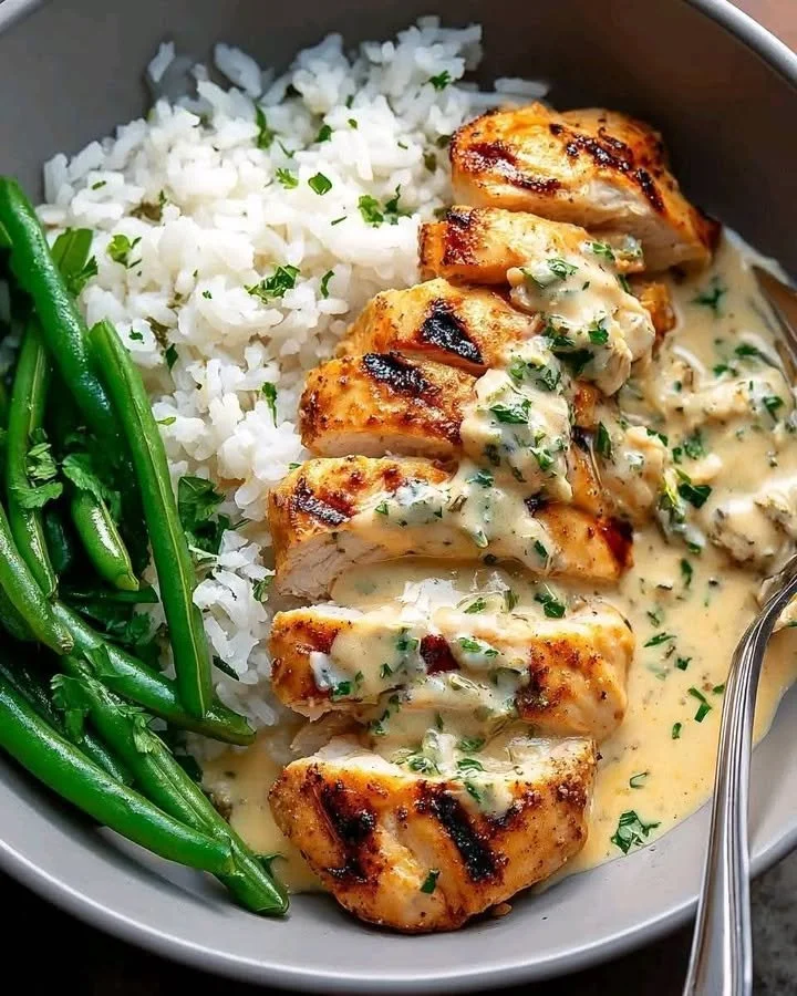 Grilled chicken bowl with creamy garlic herb sauce garnished with fresh herbs
